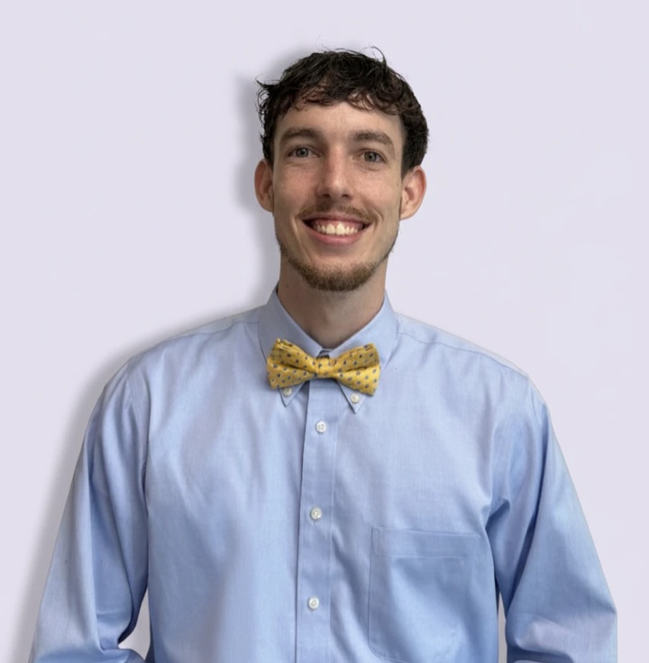 Ryan Johnston smiling in a blue button-down shirt and a yellow bow tie.